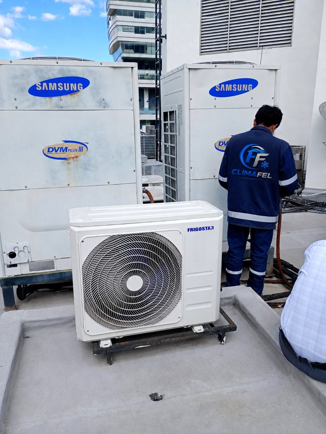 Técnico de CLIMAFEL con uniforme institucional trabajando en condensadoras Samsung sobre una azotea.